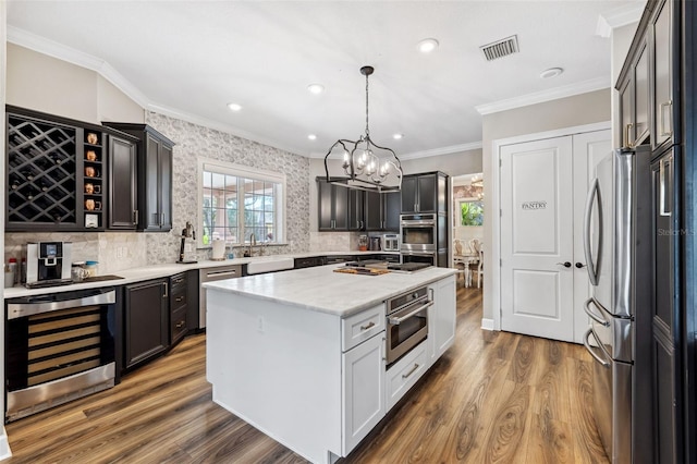 kitchen featuring pendant lighting, dark wood-type flooring, stainless steel appliances, wine cooler, and a kitchen island