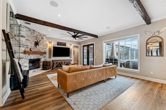 living room with french doors, a stone fireplace, hardwood / wood-style flooring, ceiling fan, and beam ceiling