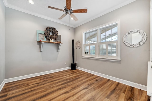 empty room with ornamental molding, wood-type flooring, and ceiling fan