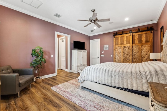 bedroom featuring hardwood / wood-style flooring, ceiling fan, ornamental molding, and a barn door