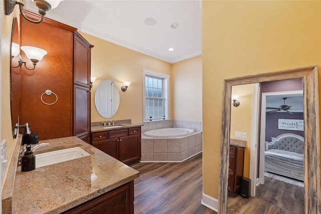 bathroom with vanity, wood-type flooring, a relaxing tiled tub, and crown molding