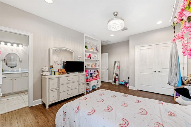 bedroom with dark hardwood / wood-style flooring, ensuite bath, and a closet