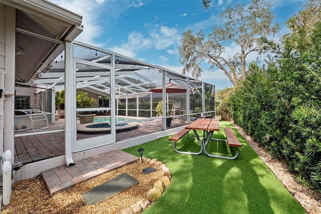 view of yard with a patio, glass enclosure, and an in ground hot tub