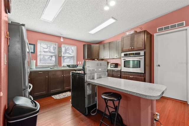 kitchen featuring vaulted ceiling, appliances with stainless steel finishes, a kitchen breakfast bar, a kitchen island, and hardwood / wood-style floors