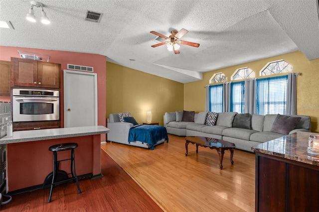 living room featuring ceiling fan, lofted ceiling, a textured ceiling, and dark hardwood / wood-style flooring