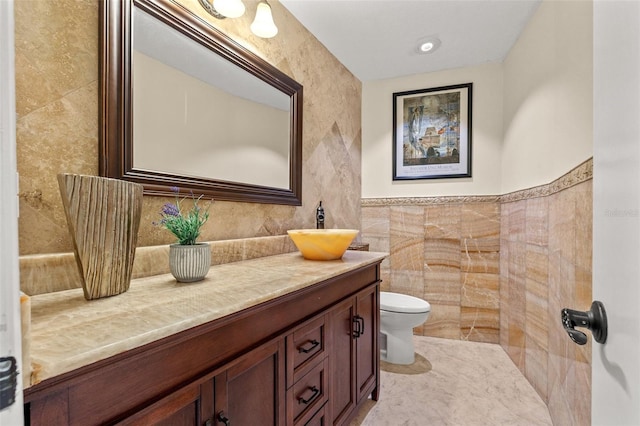 bathroom featuring vanity, toilet, and tile walls