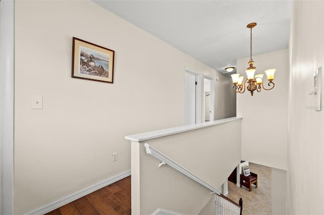 staircase with hardwood / wood-style floors and a notable chandelier