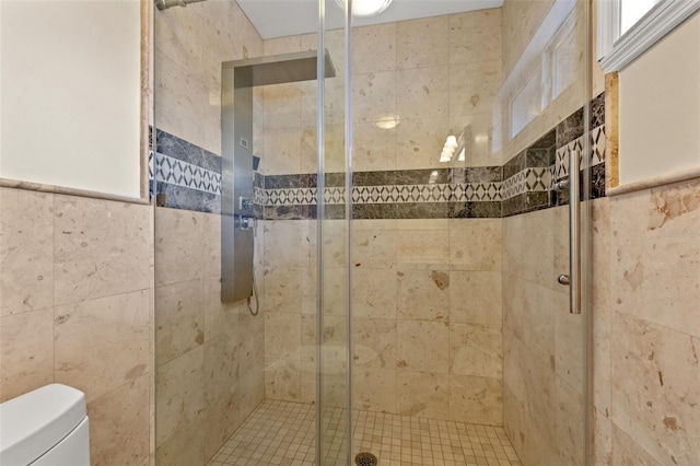 bathroom with a shower with shower door, tile walls, and toilet