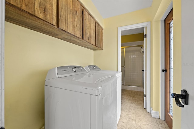 clothes washing area with cabinets and washer and dryer