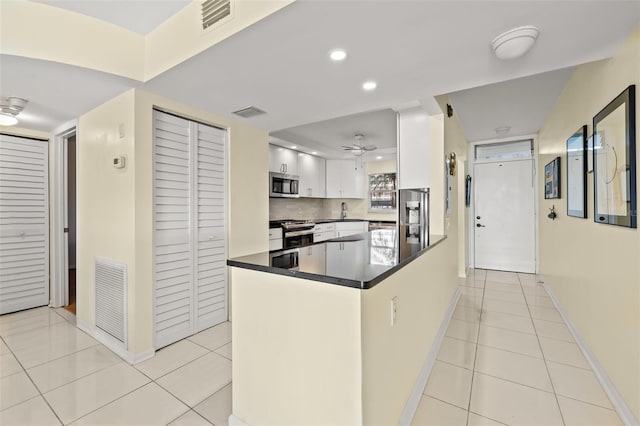 kitchen featuring sink, light tile patterned floors, appliances with stainless steel finishes, kitchen peninsula, and white cabinets