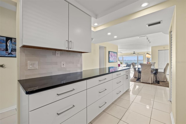 kitchen featuring backsplash, light tile patterned floors, hanging light fixtures, and white cabinets