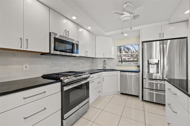 kitchen featuring light tile patterned flooring, sink, white cabinetry, stainless steel appliances, and decorative backsplash