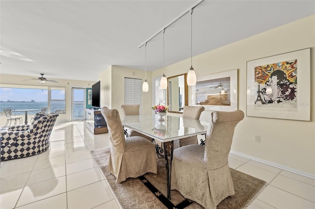 dining space featuring light tile patterned flooring, rail lighting, and a water view