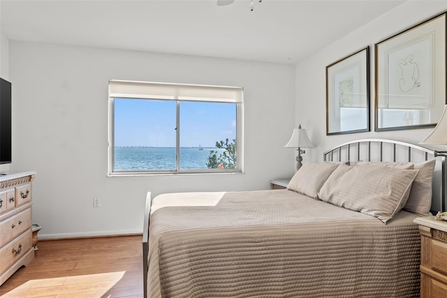 bedroom with a water view and light wood-type flooring