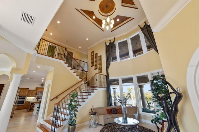 foyer with a high ceiling, crown molding, and decorative columns