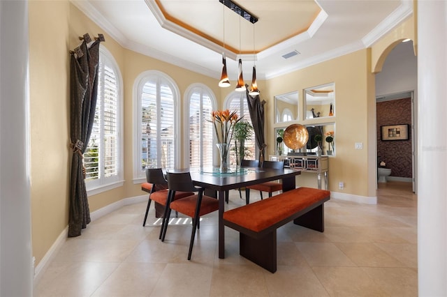 dining area featuring crown molding, a tray ceiling, and light tile patterned flooring