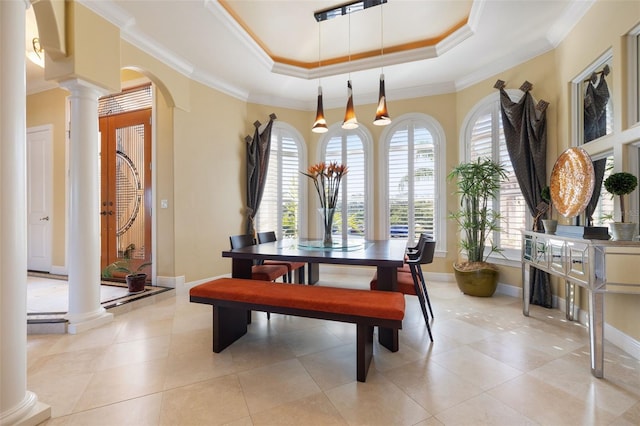 dining area with crown molding, plenty of natural light, a tray ceiling, and ornate columns