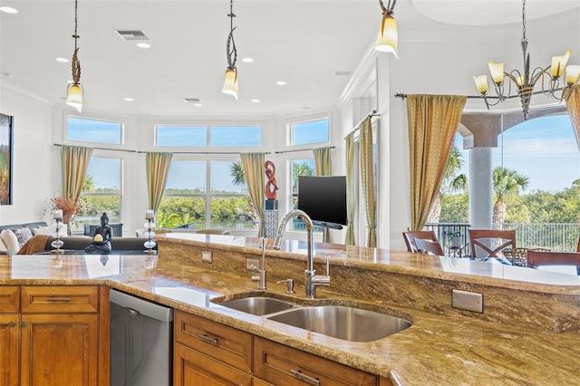 kitchen featuring pendant lighting, dishwasher, sink, and light stone countertops