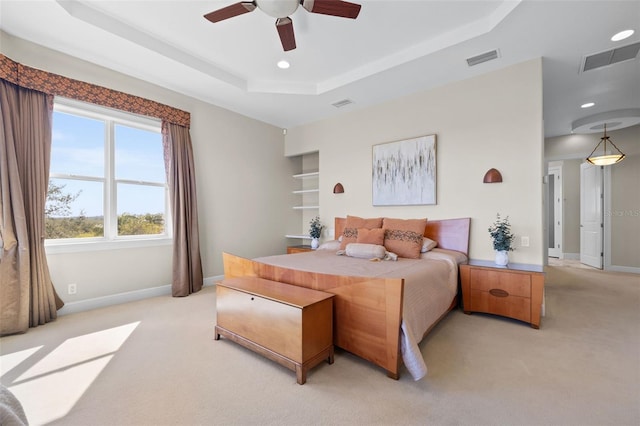 carpeted bedroom with a tray ceiling and ceiling fan