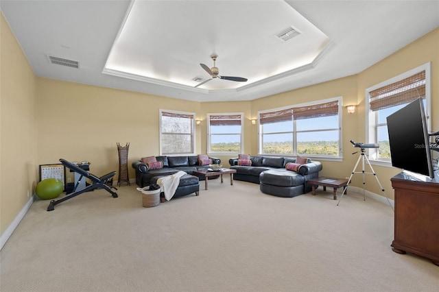 living room featuring a raised ceiling, light carpet, and ceiling fan