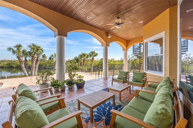 view of patio with an outdoor living space, a water view, and ceiling fan