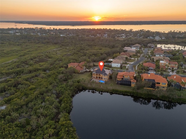 aerial view at dusk featuring a water view