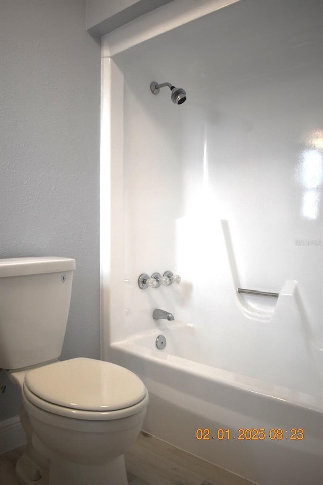 bathroom featuring hardwood / wood-style flooring, bathing tub / shower combination, and toilet