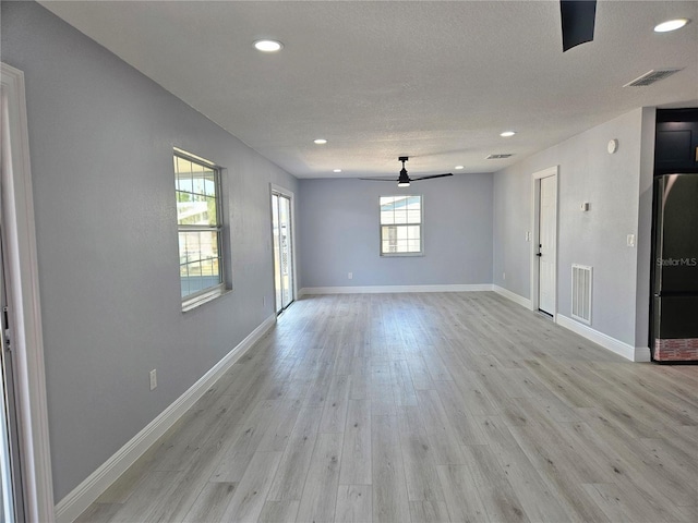 empty room with ceiling fan, light hardwood / wood-style flooring, and a textured ceiling