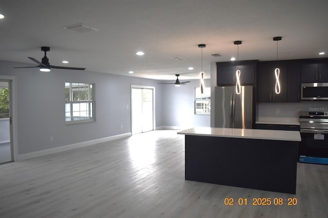 kitchen with pendant lighting, appliances with stainless steel finishes, a center island, and light wood-type flooring