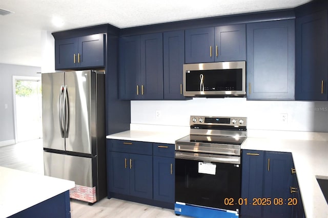 kitchen featuring blue cabinetry, stainless steel appliances, light hardwood / wood-style flooring, and a textured ceiling