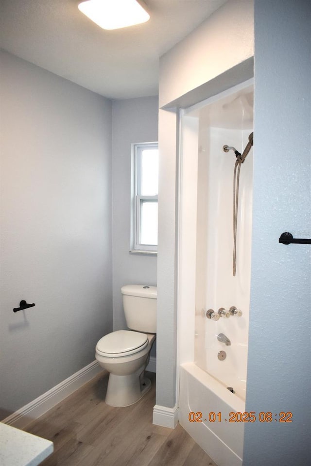 bathroom featuring hardwood / wood-style floors, bathing tub / shower combination, and toilet