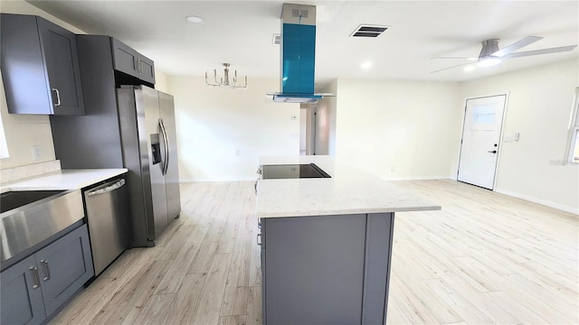 kitchen featuring light stone countertops, island exhaust hood, appliances with stainless steel finishes, and light hardwood / wood-style flooring