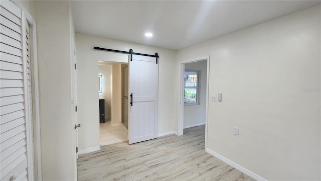 corridor with a barn door and light hardwood / wood-style floors