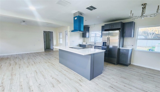 kitchen with pendant lighting, stainless steel appliances, light hardwood / wood-style floors, and island range hood