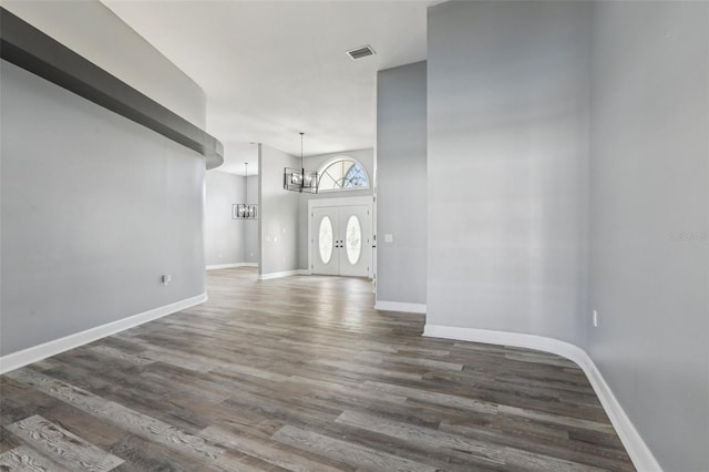 foyer entrance featuring dark wood-type flooring, a chandelier, and a towering ceiling