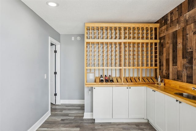 wine room with dark hardwood / wood-style flooring, sink, a textured ceiling, and wood walls