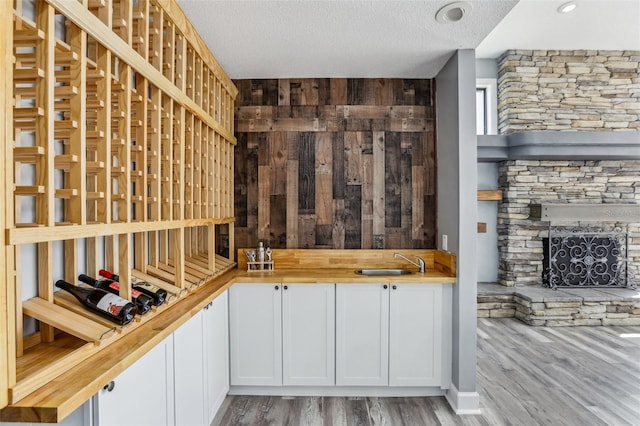 wine cellar featuring wooden walls, a fireplace, wood-type flooring, sink, and a textured ceiling