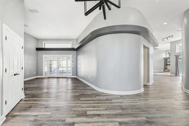 hall with hardwood / wood-style floors, rail lighting, and french doors