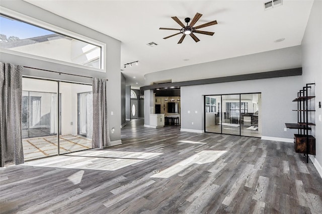 unfurnished living room with hardwood / wood-style floors, ceiling fan, and a high ceiling