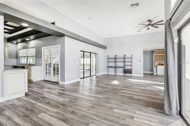 unfurnished living room with hardwood / wood-style flooring, ceiling fan, and french doors