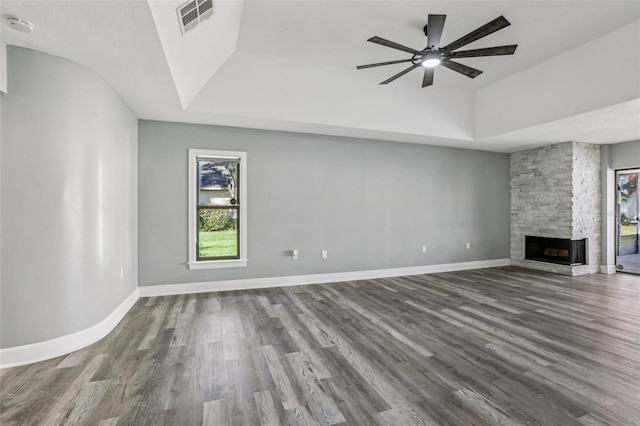 unfurnished living room with ceiling fan, wood-type flooring, a fireplace, and a tray ceiling