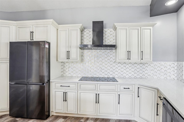 kitchen with black electric cooktop, stainless steel fridge, tasteful backsplash, and wall chimney exhaust hood