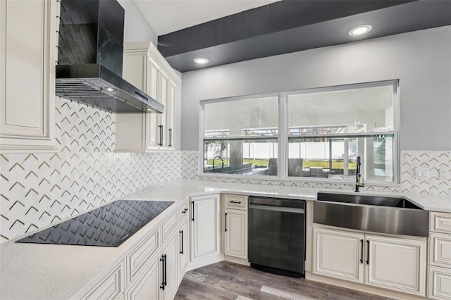 kitchen with wall chimney range hood, sink, dark wood-type flooring, tasteful backsplash, and black appliances