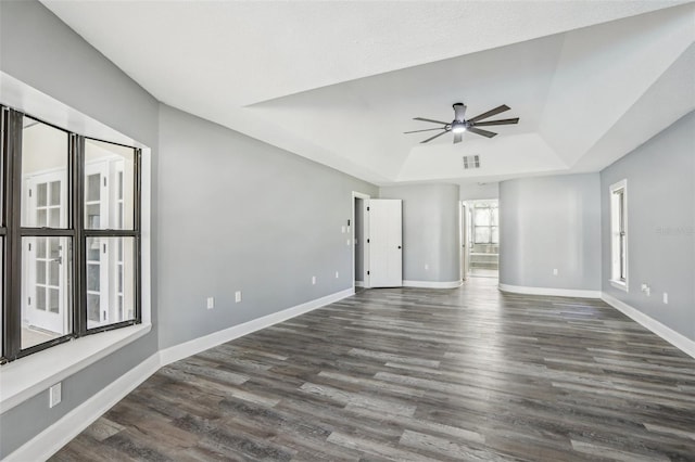 unfurnished room with a raised ceiling, ceiling fan, and dark hardwood / wood-style flooring