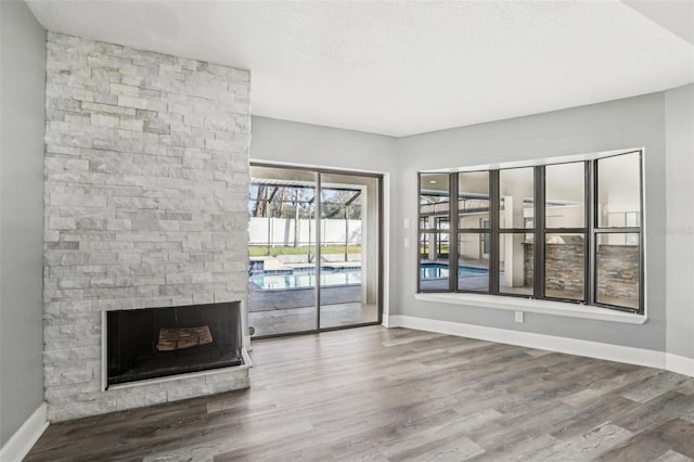 unfurnished living room with wood-type flooring, a textured ceiling, and a fireplace