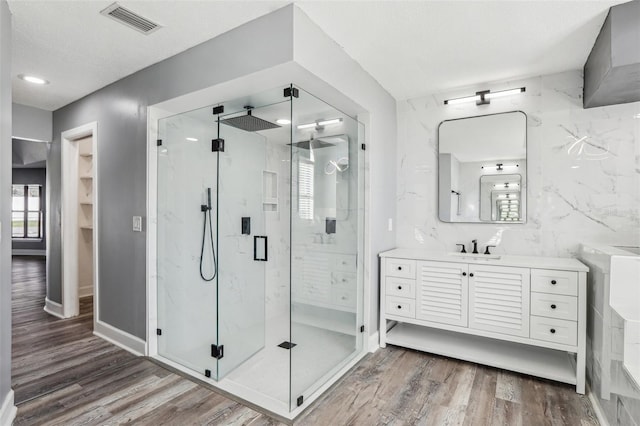 bathroom featuring wood-type flooring, an enclosed shower, a textured ceiling, and vanity