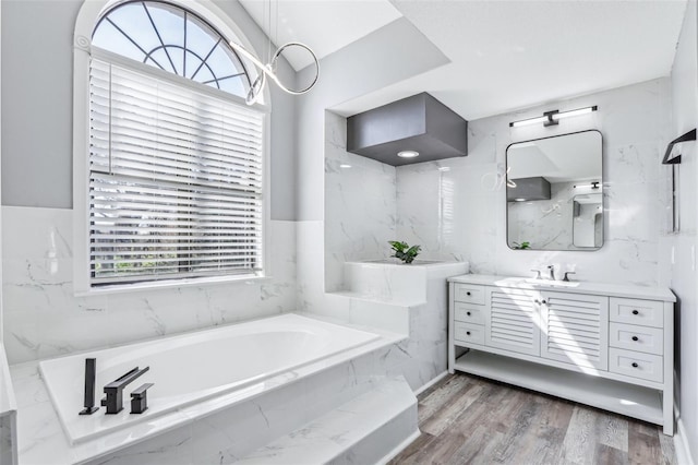 bathroom with tiled tub, vanity, and hardwood / wood-style floors