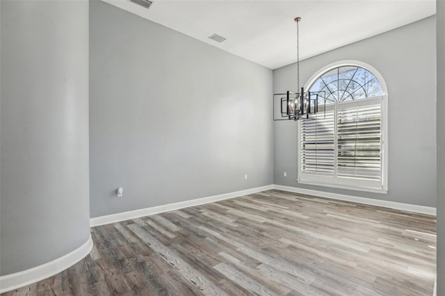 unfurnished dining area featuring an inviting chandelier and wood-type flooring