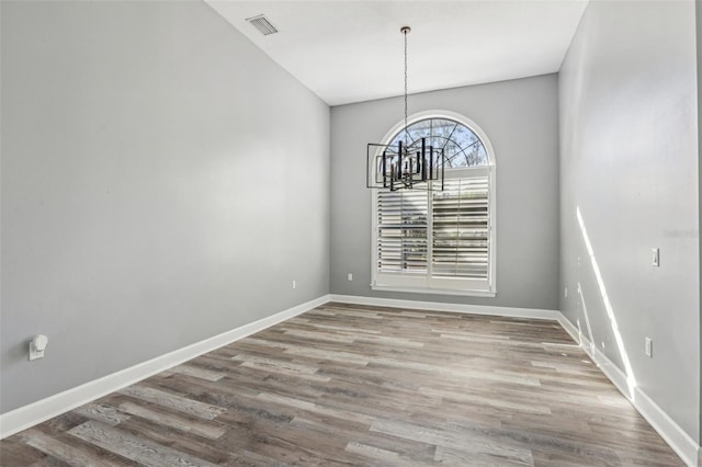 unfurnished dining area featuring an inviting chandelier and hardwood / wood-style flooring