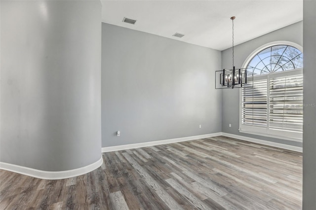 unfurnished dining area with an inviting chandelier and hardwood / wood-style floors